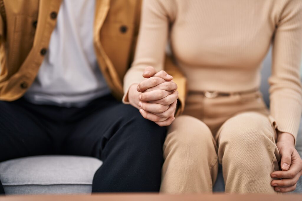 Mand and woman couple sitting on sofa with hands together at home